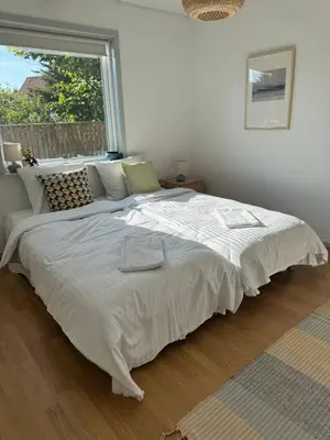 a large white bed in a bedroom with a window at Viking Surf Home in Klitmøller