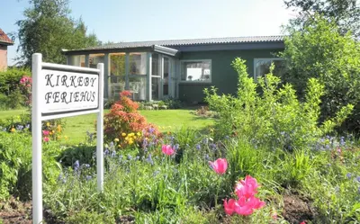 a sign in front of a house with flowers at Holiday Home Kirkeby Feriehus in Roslev
