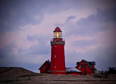 a red lighthouse sitting on top of a hill at Guldmark in Lemvig