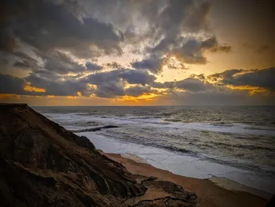 a sunset over the ocean with a rocky beach at Guldmark in Lemvig