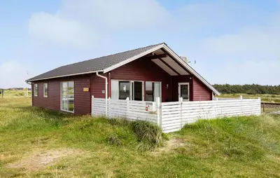 a small red house with a white fence in a field at Awesome Home In Harboøre in Harboør