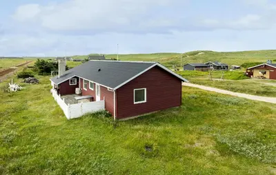 a small red house in a field of grass at Awesome Home In Harboøre in Harboør