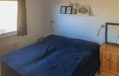 a bedroom with a blue bed and a window at Awesome Home In Harboøre in Harboør