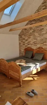a wooden bed in a room with a brick wall at Koppes Mølle B&B - naturnær overnatning in Borup