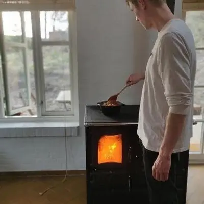 a man standing in front of a stove at Koppes Mølle B&B - naturnær overnatning in Borup