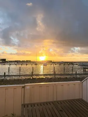 a sunset over the water with a pier at Cozy harbor house in Nibe in Nibe