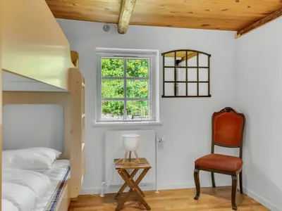 a bedroom with a bed and a chair and a window at Holiday Home Åsta - 400m to the fjord by Interhome in Roslev