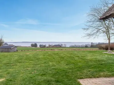 a large grassy field with a barn in the background at Holiday Home Åsta - 400m to the fjord by Interhome in Roslev