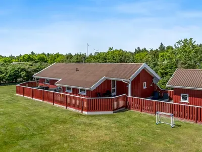 a red house with a fence and a soccer ball at Holiday Home Hans - 1-2km from the sea by Interhome in Løkken