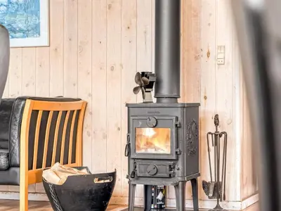 a wood stove in a living room with a chair at Holiday Home Hans - 1-2km from the sea by Interhome in Løkken