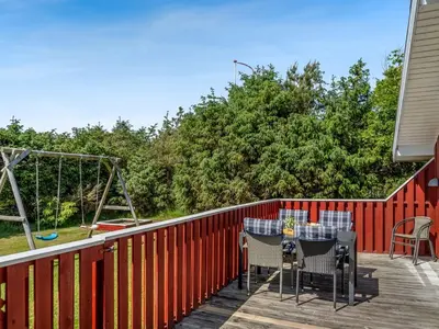 a patio with tables and chairs on a red fence at Holiday Home Hans - 1-2km from the sea by Interhome in Løkken