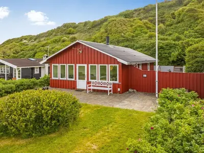 a red house with a bench in front of a hill at Holiday Home Blia - 120m to the fjord by Interhome in Løgstør