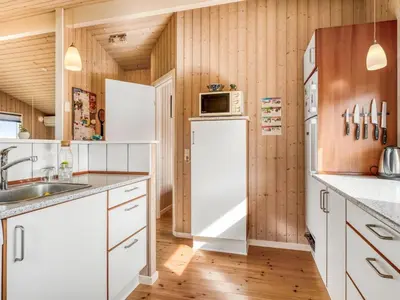 a kitchen with white appliances and wooden walls at Holiday Home Fridgerd - 300m from the sea by Interhome in Løkken