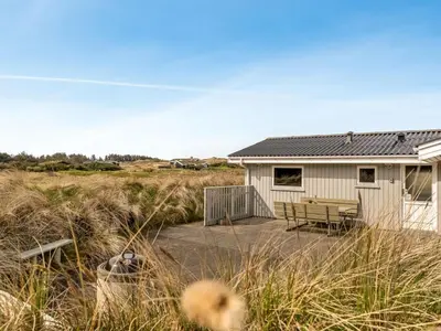 a house with a table and a bench on a patio at Holiday Home Fridgerd - 300m from the sea by Interhome in Løkken