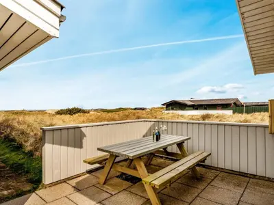 a wooden picnic table on a fence with a house in the background at Holiday Home Fridgerd - 300m from the sea by Interhome in Løkken