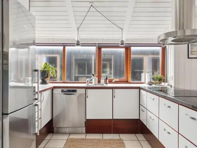 a kitchen with white cabinets and a large window at Holiday Home Sinika - 100m from the sea by Interhome in Blokhus