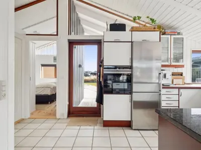 a kitchen with a refrigerator and a door to a bedroom at Holiday Home Sinika - 100m from the sea by Interhome in Blokhus