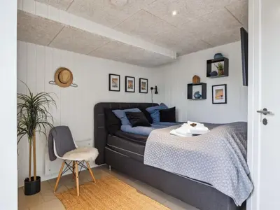 a bedroom with a bed and a chair at Holiday Home Sinika - 100m from the sea by Interhome in Blokhus