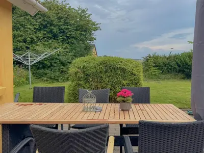 a wooden table with chairs and flowers on a patio at Holiday Home Elza - 2-5km from the sea by Interhome in Fjerritslev