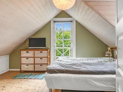 a bedroom with a bed and a tv and a window at Holiday Home Elza - 2-5km from the sea by Interhome in Fjerritslev