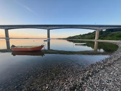 a boat sitting on the water under a bridge at Motel Glyngøre in Roslev