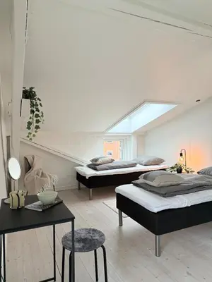 a room with two beds and a table with a chair at Cozy Pearl in Viborg Centre in Viborg
