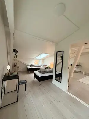 a large white room with a bed and a mirror at Cozy Pearl in Viborg Centre in Viborg