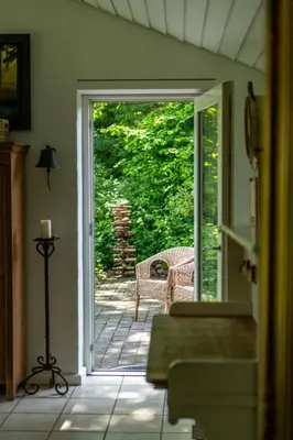 an open door to a patio with a wicker chair at Country House With Fjord Views At Harre Vig in Roslev