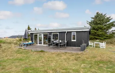 a black tiny house with a deck in a field at Pet Friendly Home In Thisted With Wifi in Thisted