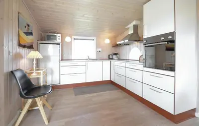 a kitchen with white cabinets and a black chair at 2 Bedroom Pet Friendly Home In Thisted in Thisted