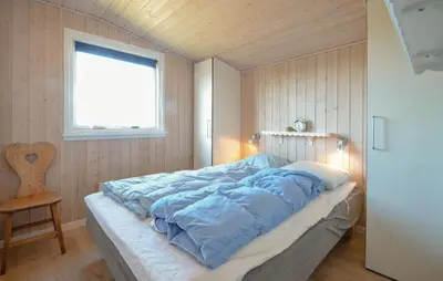 a bed with blue sheets in a room with a window at 2 Bedroom Pet Friendly Home In Thisted in Thisted