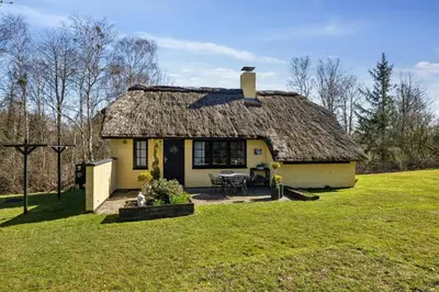 a small yellow house with a grass roof at Astrup Vig Hideaway, Thatched Cottage with Shelter & Serenity in Roslev