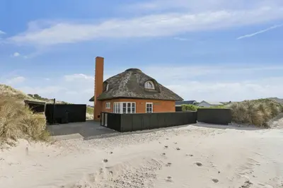 a house with a thatched roof on the beach at Thatched Holiday Home By The North Sea In Blokhus in Blokhus