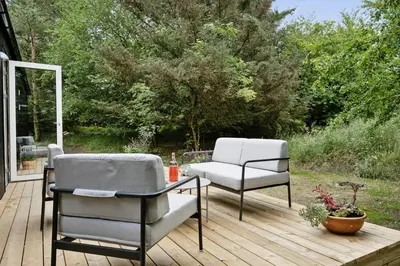 a patio with two chairs and a table on a deck at Architect-Designed Wooden House At Ertebølle in Farsø