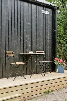 a table and chairs on a wooden deck with a black building at Architect-Designed Wooden House At Ertebølle in Farsø