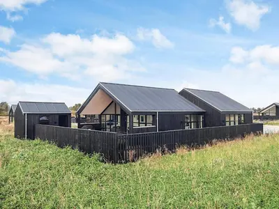 a black house with a black roof in a field at 5 star holiday home in Løkken in Løkken