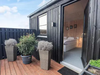 a black shipping container with potted plants on a deck at 5 star holiday home in Løkken in Løkken