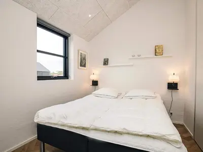 a white bedroom with a large bed with two pillows at 5 star holiday home in Løkken in Løkken