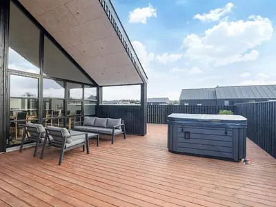 a deck with a hot tub and chairs on a roof at 5 star holiday home in Løkken in Løkken