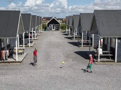 two children playing with a ball in the middle of a row of houses at 4 star holiday home in Thyborøn in Thyborøn