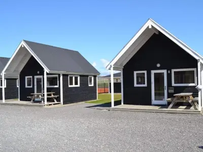 two black buildings with picnic tables in front of them at 4 star holiday home in Thyborøn in Thyborøn