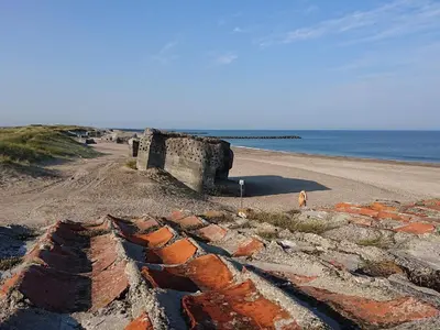 a person standing on a beach next to the ocean at 4 star holiday home in Thyborøn in Thyborøn