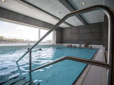 a large swimming pool with people in the water at 4 star holiday home in Thyborøn in Thyborøn