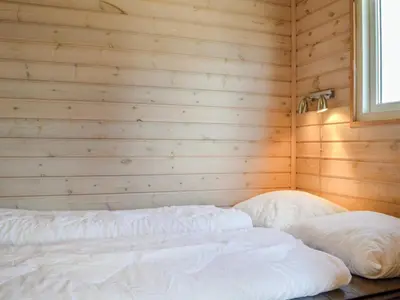 a bedroom with a white bed in a wooden wall at 4 star holiday home in Thyborøn in Thyborøn
