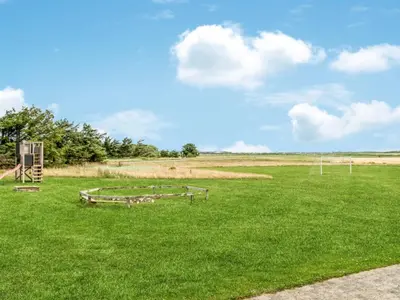 a grassy field with two benches in the grass at 4 star holiday home in Harboøre in Harboør
