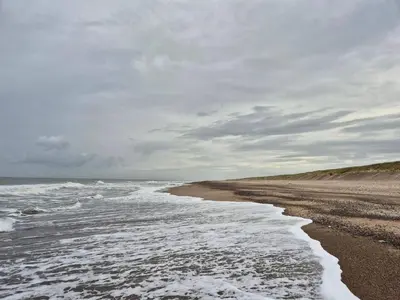 an empty beach with waves on a cloudy day at 4 star holiday home in Harboøre in Harboør
