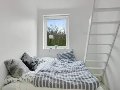a bedroom with a bed and a ladder and a window at 4 star holiday home in Blokhus in Blokhus