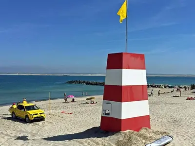 a yellow car parked next to a red and white lighthouse on a beach at 4 star holiday home in Thyborøn in Thyborøn