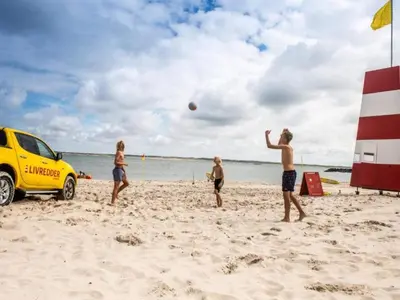 a group of people playing with a ball on the beach at 4 star holiday home in Thyborøn in Thyborøn