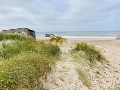 a sandy beach with some grass and the ocean at 4 star holiday home in Thyborøn in Thyborøn